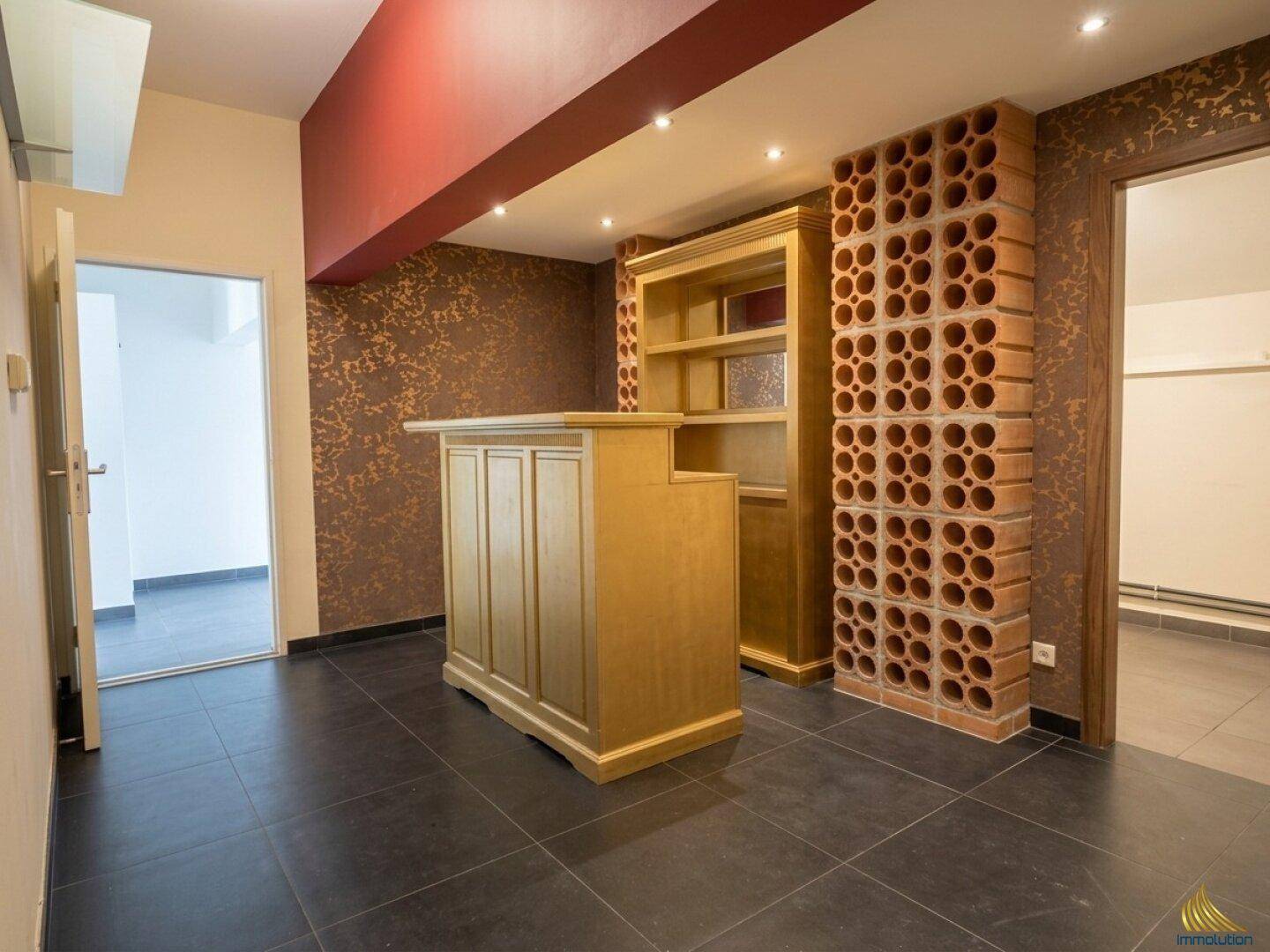Ausgebauter Kellerraum mit Bar, dekorativer Ziegelwand und dunklem Fliesenboden.