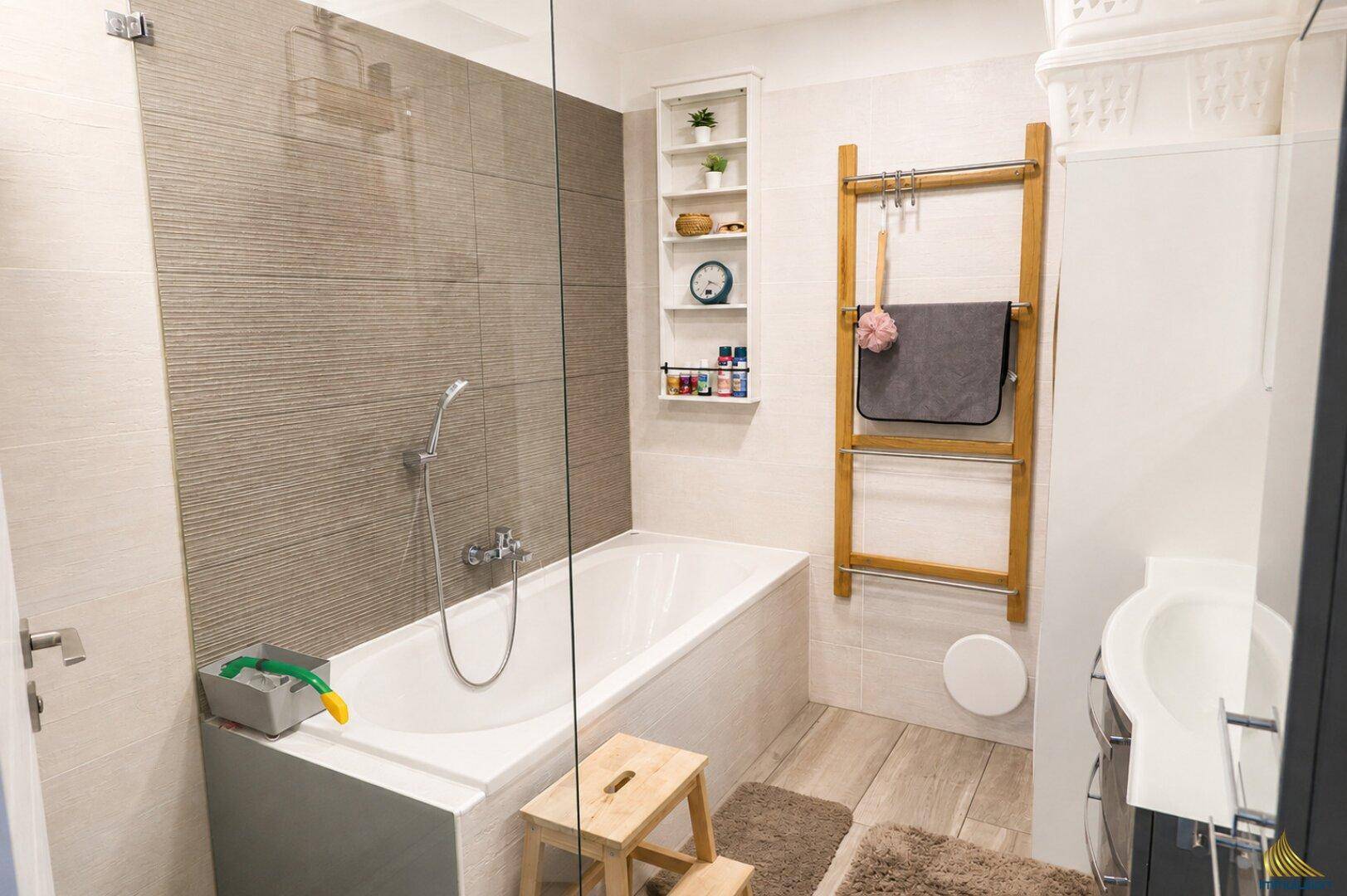 Modernes Badezimmer mit Badewanne, Duschfunktion und hellen Fliesen, funktional eingerichtet.