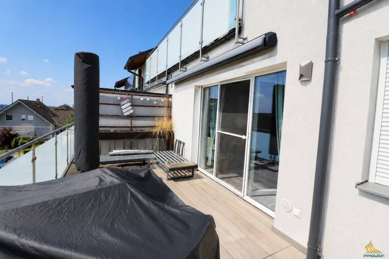 Große Dachterrasse mit Holzboden und Glasgeländer, ideal für Entspannung im Freien.