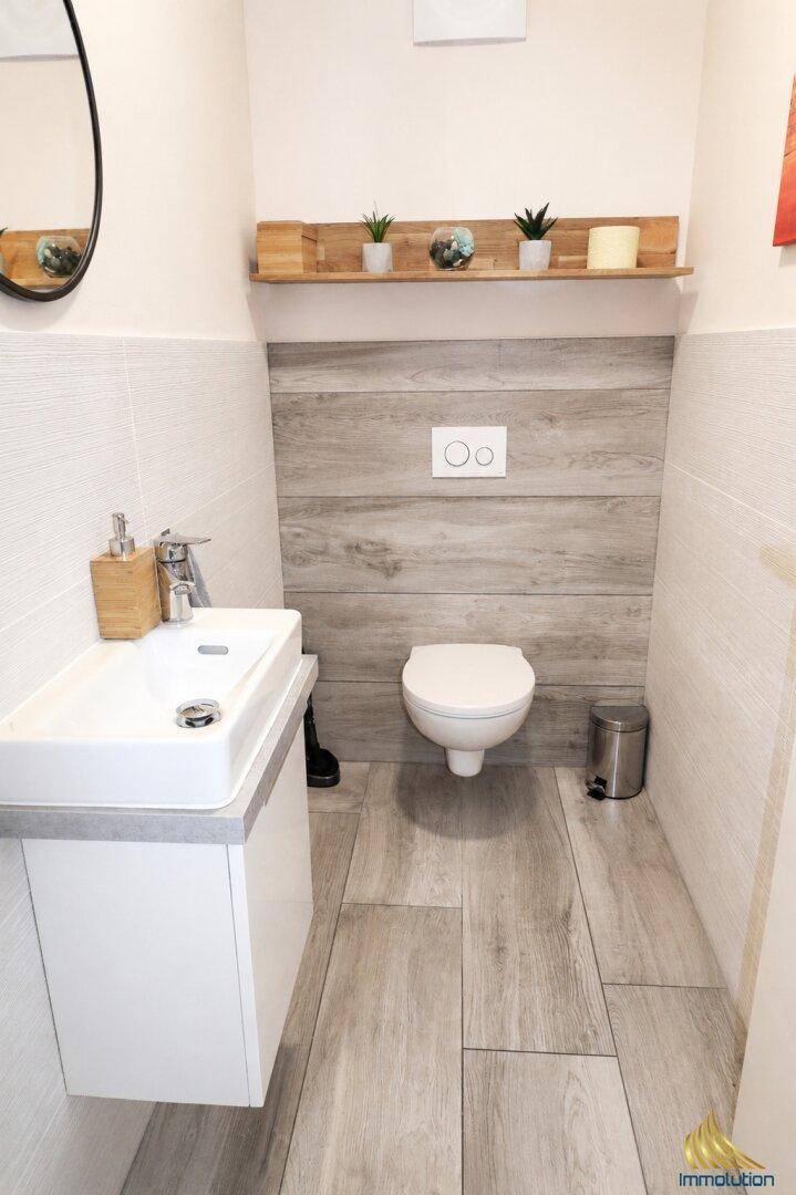 Kleines Gäste-WC mit wandhängendem WC, modernem Waschbecken und Holzoptik-Fliesen.