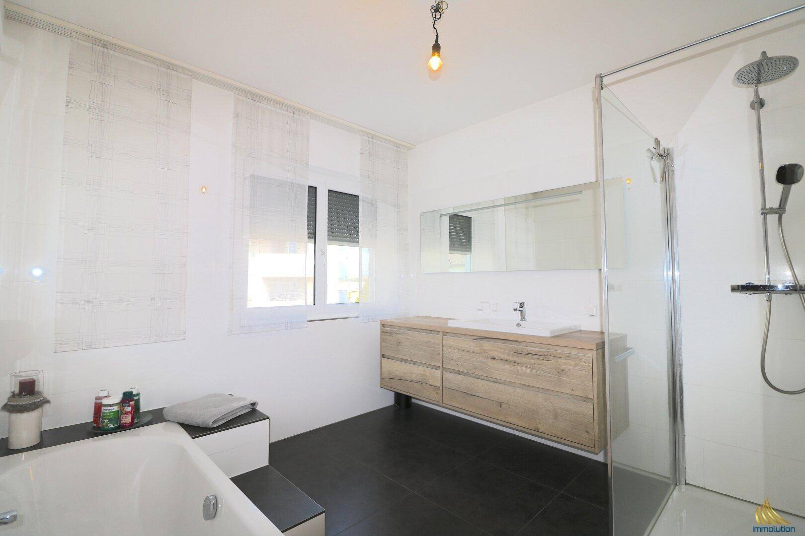 Modernes Badezimmer mit Dusche, Badewanne, Holzwaschtisch und Fenster für gute Belüftung.