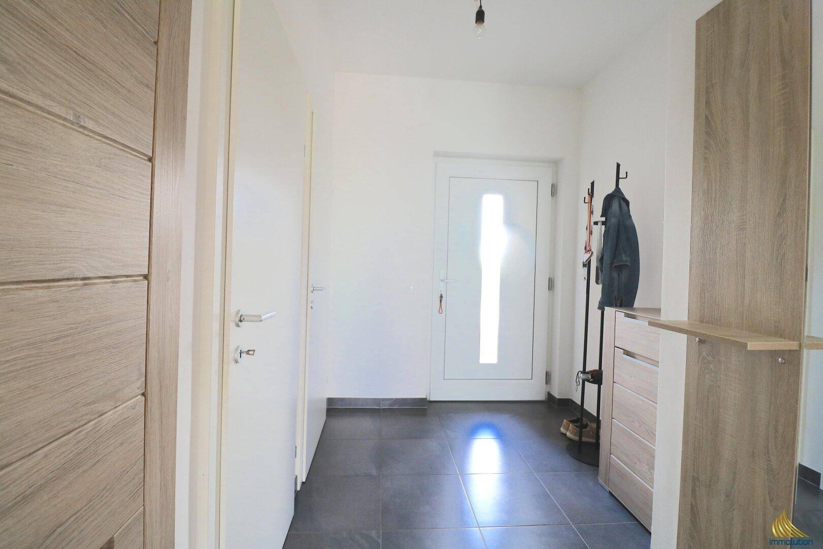 Heller Eingangsbereich mit Fliesenboden, Garderobe und moderner Haustür.