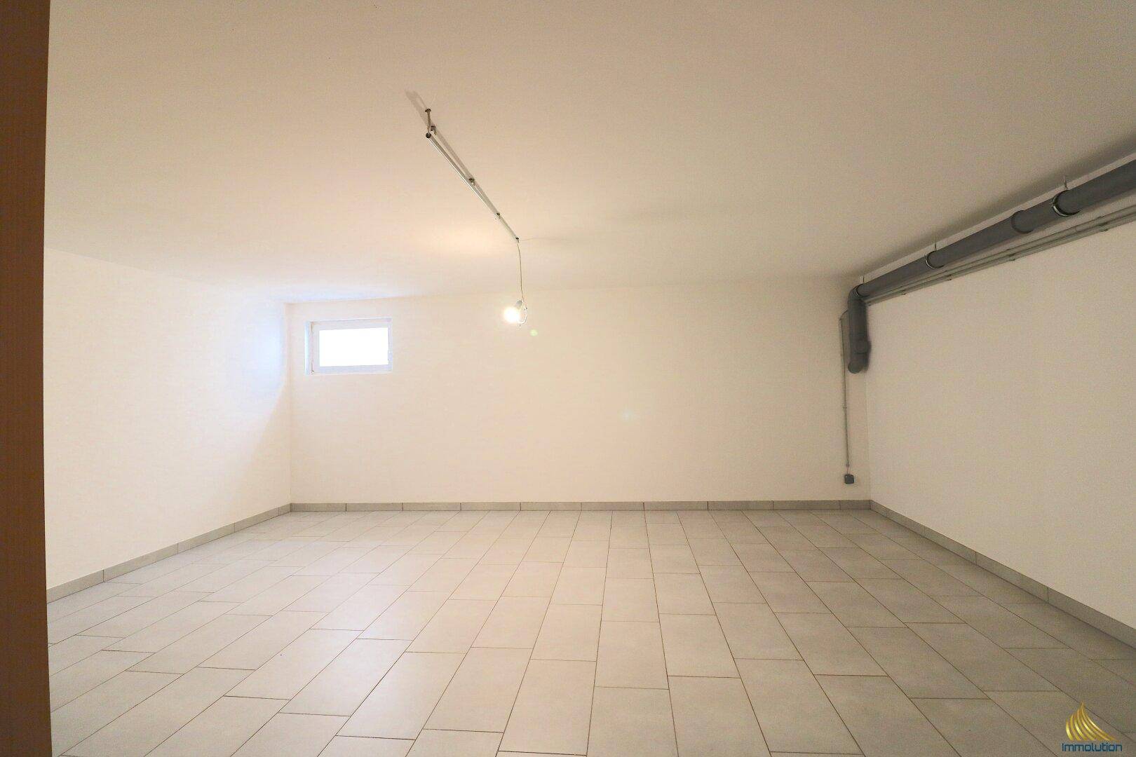 Geräumiger, gefliester Kellerraum mit kleinem Fenster, ideal als Abstellfläche.