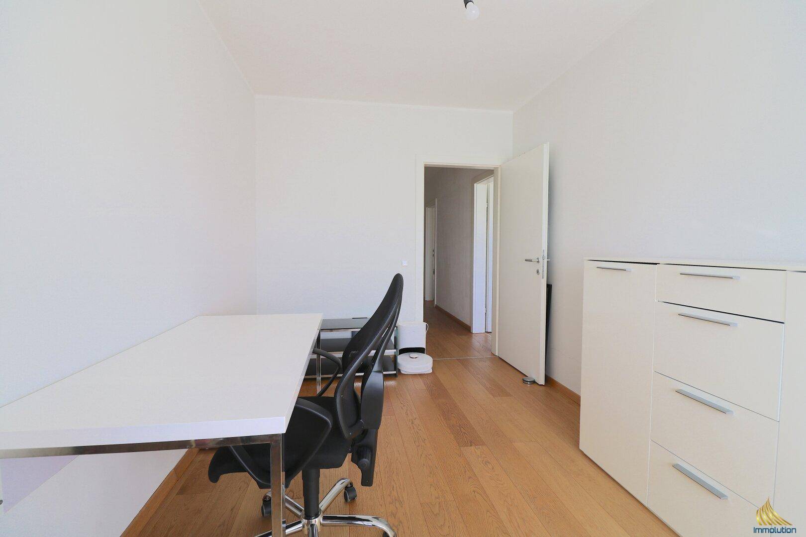 Helles Arbeitszimmer mit Holzboden, weißem Schreibtisch und viel Platz für Produktivität.