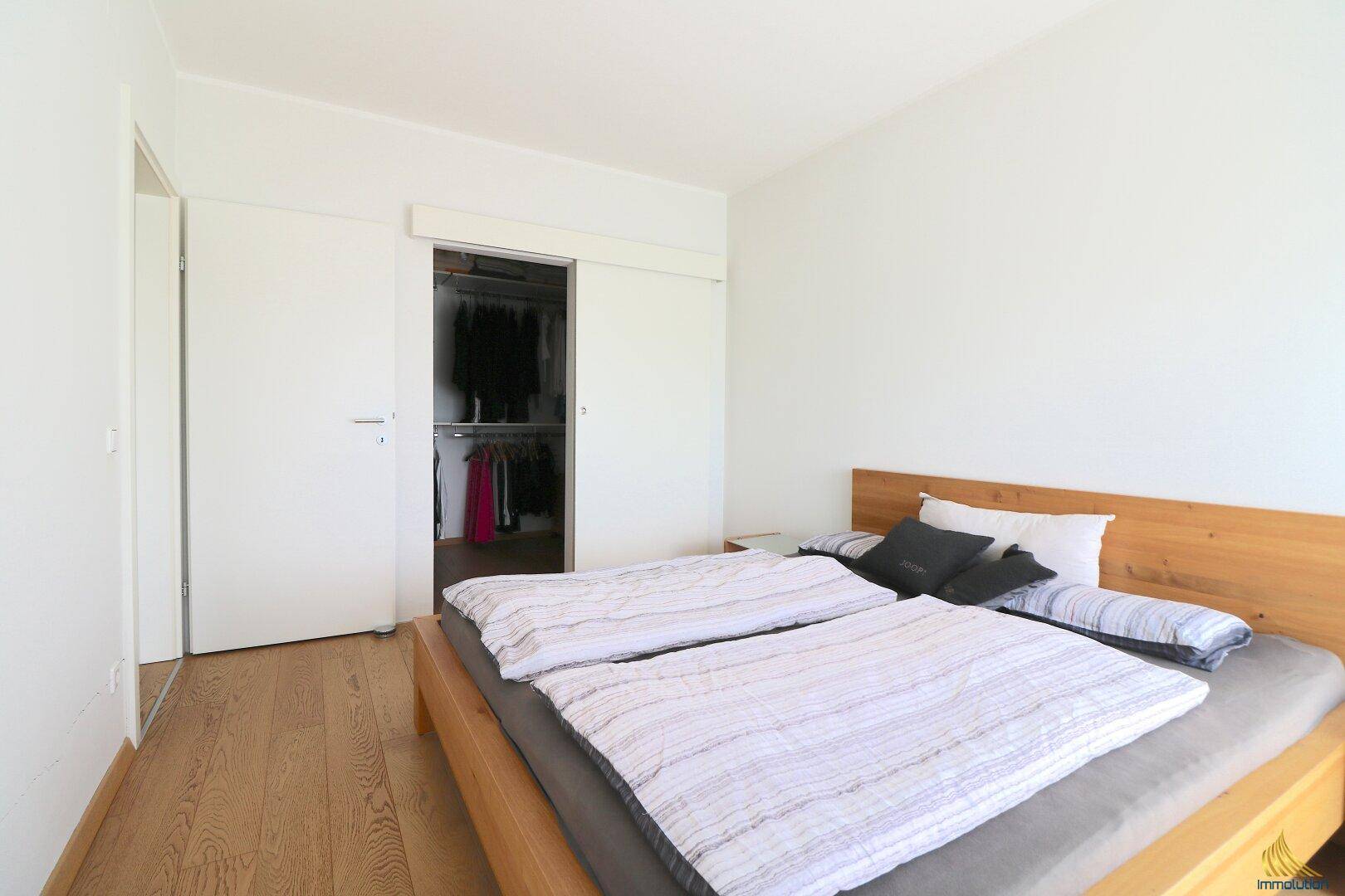 Schlafzimmer mit Holzboden und praktischer Schiebetür zum begehbaren Kleiderschrank.