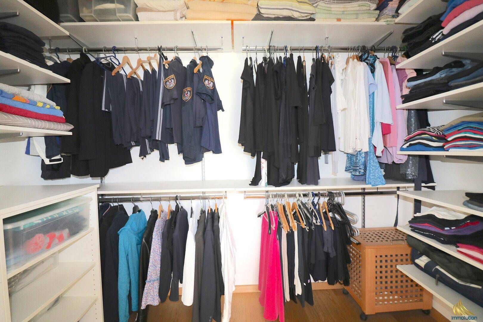 Geräumiger begehbarer Kleiderschrank mit vielen Ablagemöglichkeiten und Kleiderstangen.