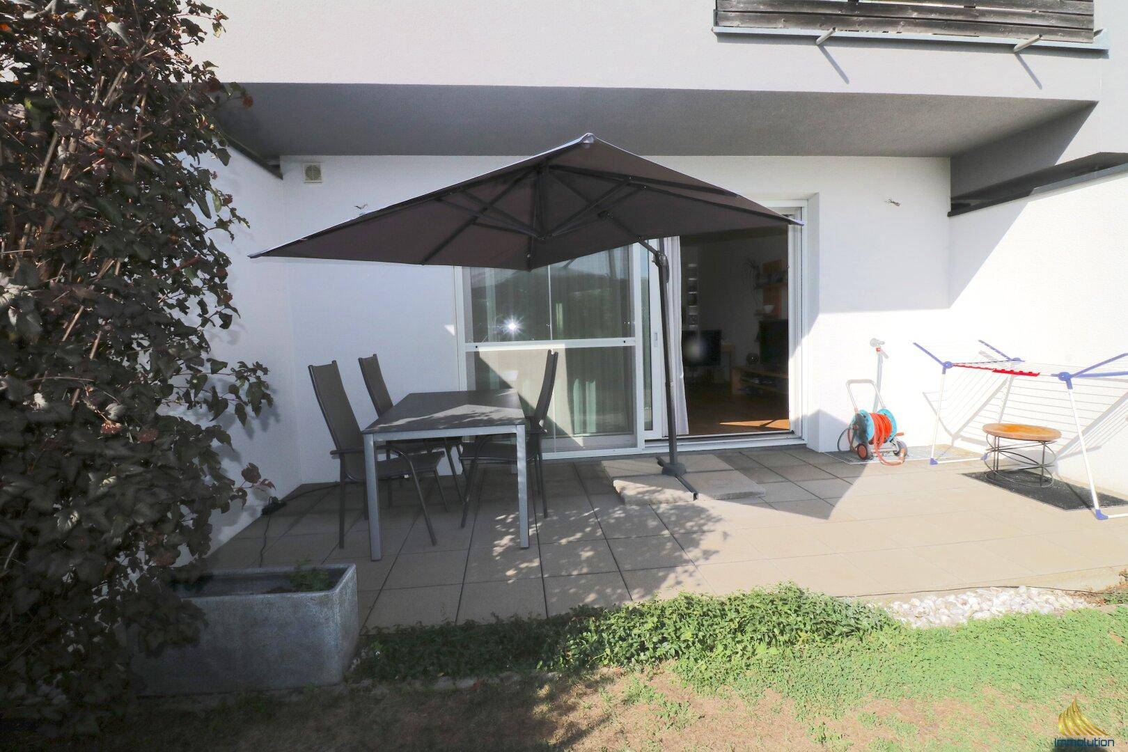 Terrasse mit Esstisch, großem Sonnenschirm und direktem Zugang zum Garten.