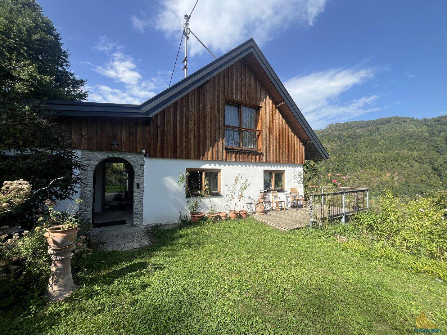 Gemütliches Landhaus mit Holzelementen und kleiner Terrasse, ideal für entspannte Stunden im Grünen.