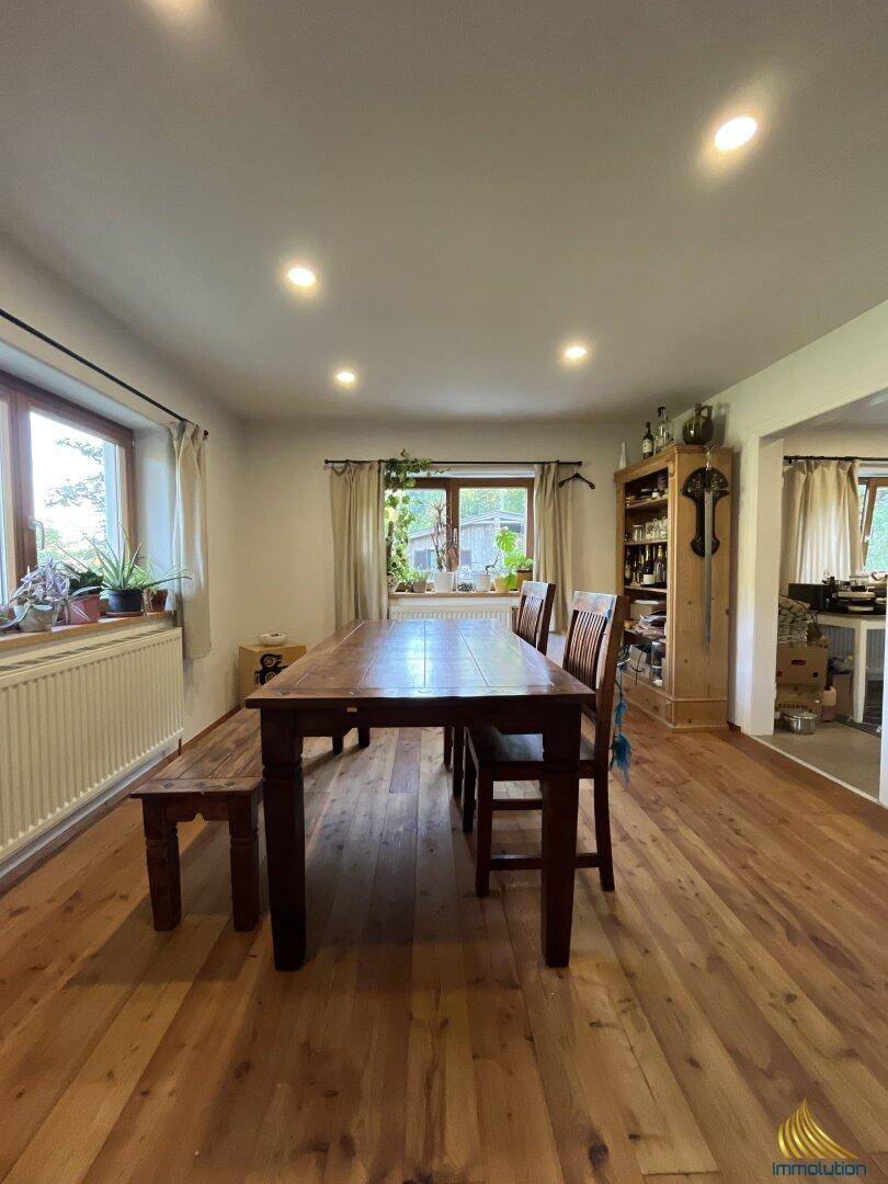 Geräumiger Essbereich mit großem Holztisch, Holzboden und viel Tageslicht durch die Fenster.