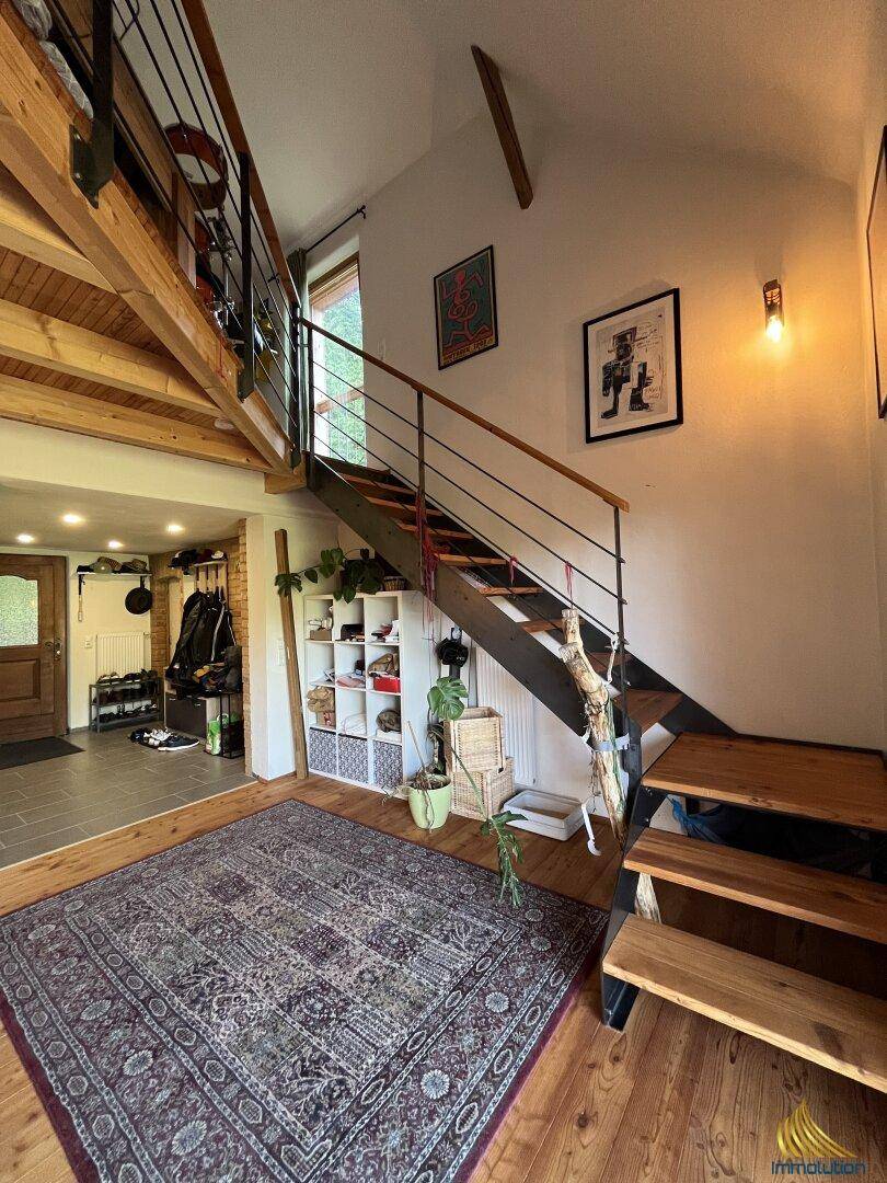 Heller Eingangsbereich mit offener Holztreppe, Holzboden und dekorativem Teppich.