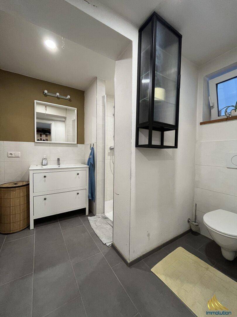 Modernes Badezimmer mit Dusche, Einzelwaschbecken und Fenster für natürliche Belüftung.