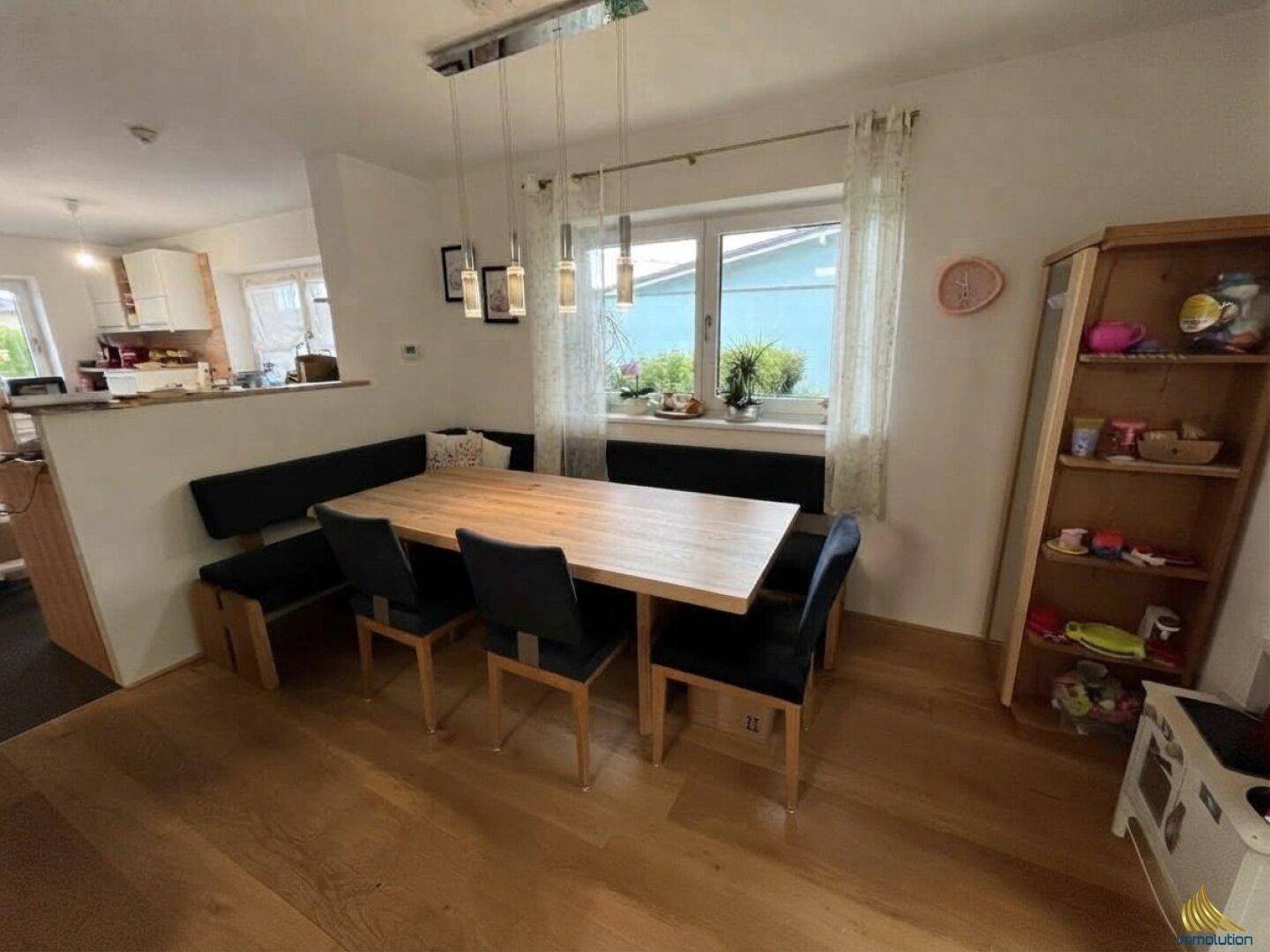 Gemütlicher Essbereich mit Holztisch und Sitzbank, offen zur Küche, mit Blick nach draußen.
