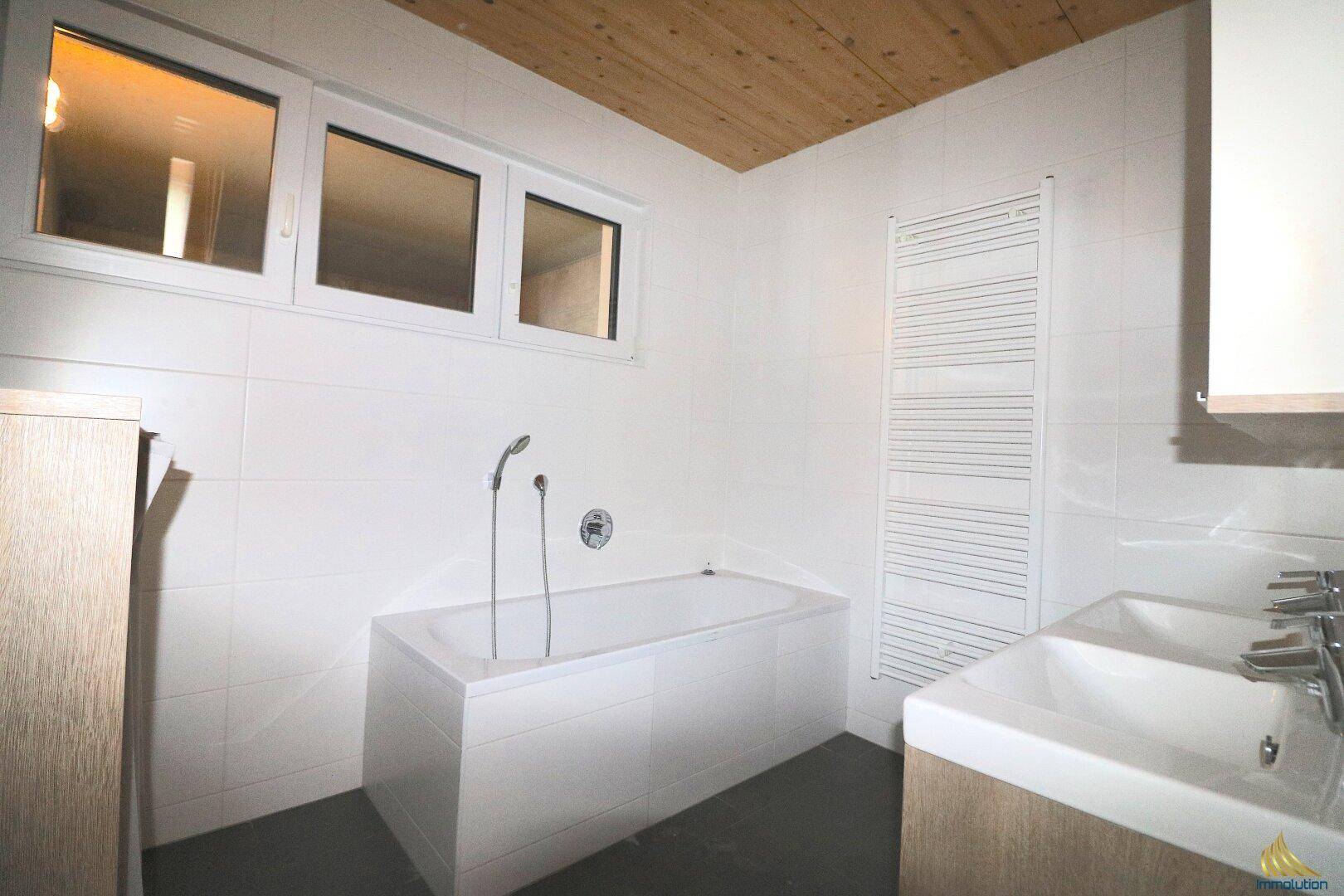 Helles Badezimmer mit Badewanne, Fenster und modernem Waschtisch, ideal für Entspannung.