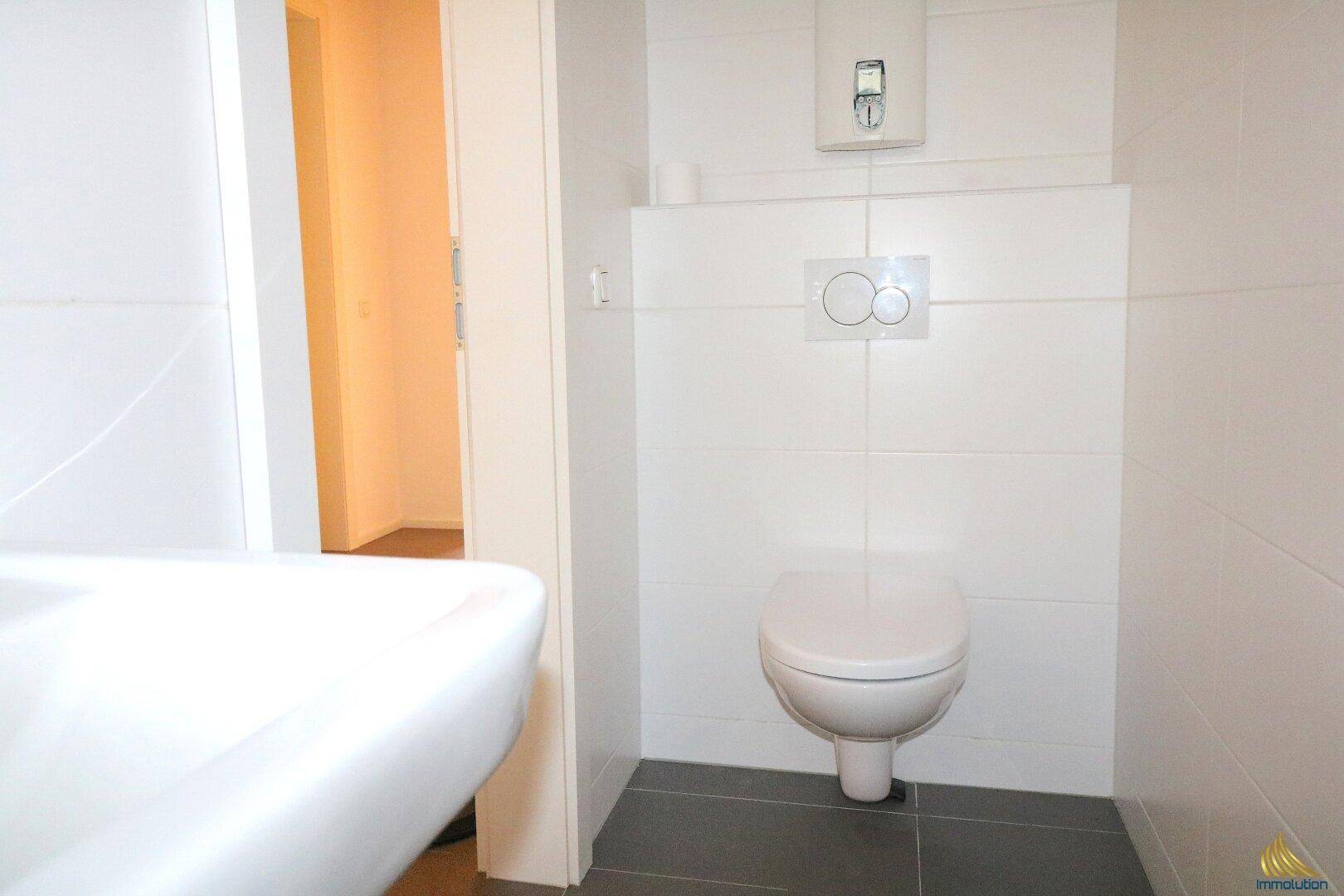 Funktionelles Gäste-WC mit wandhängender Toilette und kleinem Waschbecken.