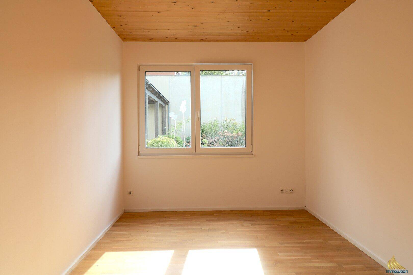 Helles Zimmer mit Holzboden und Fenster zum Garten, vielseitig nutzbar als Schlaf- oder Arbeitszimmer.