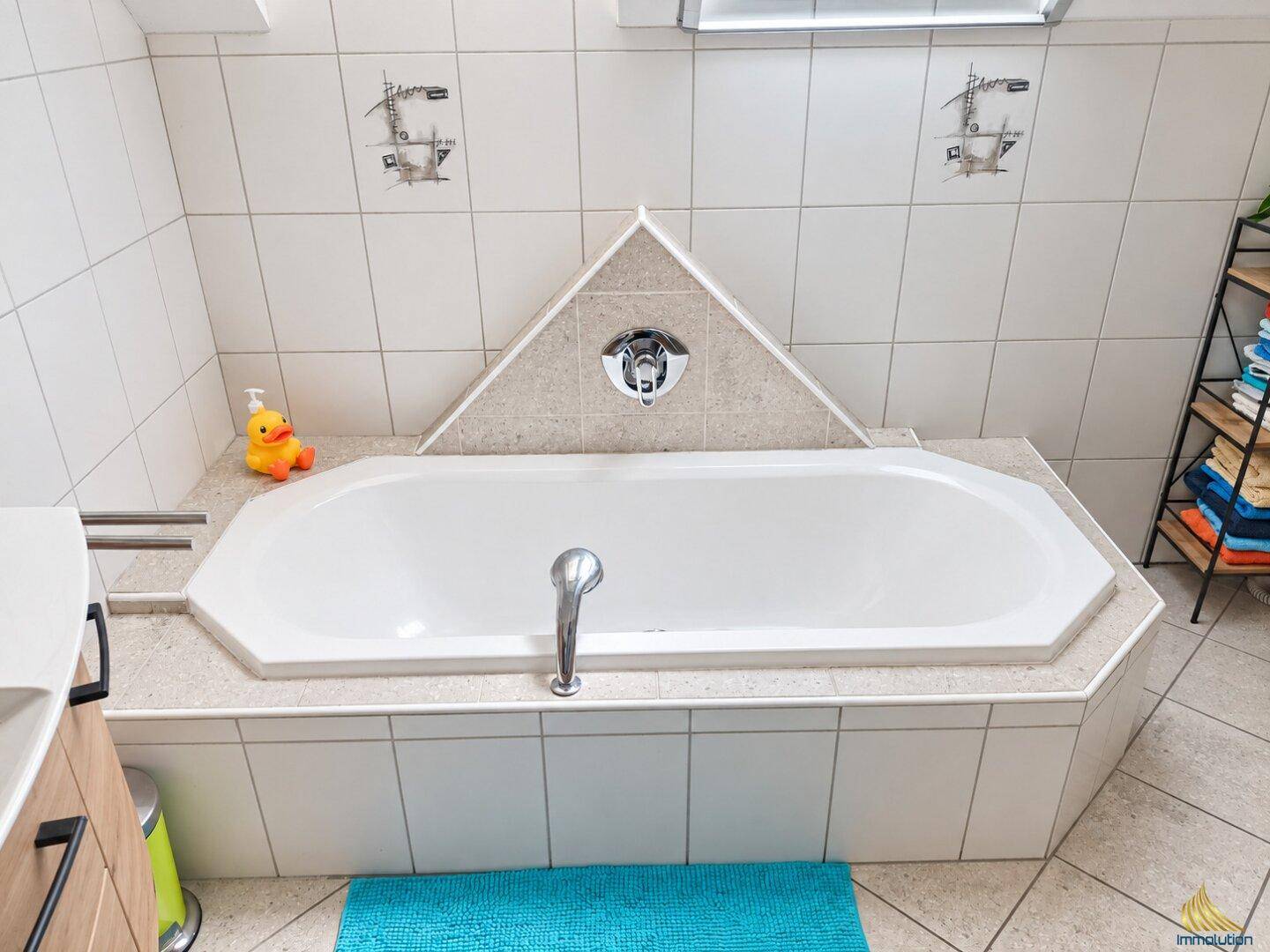 Badezimmer mit eingebauter Eckbadewanne und hellen Fliesen, funktional gestaltet.
