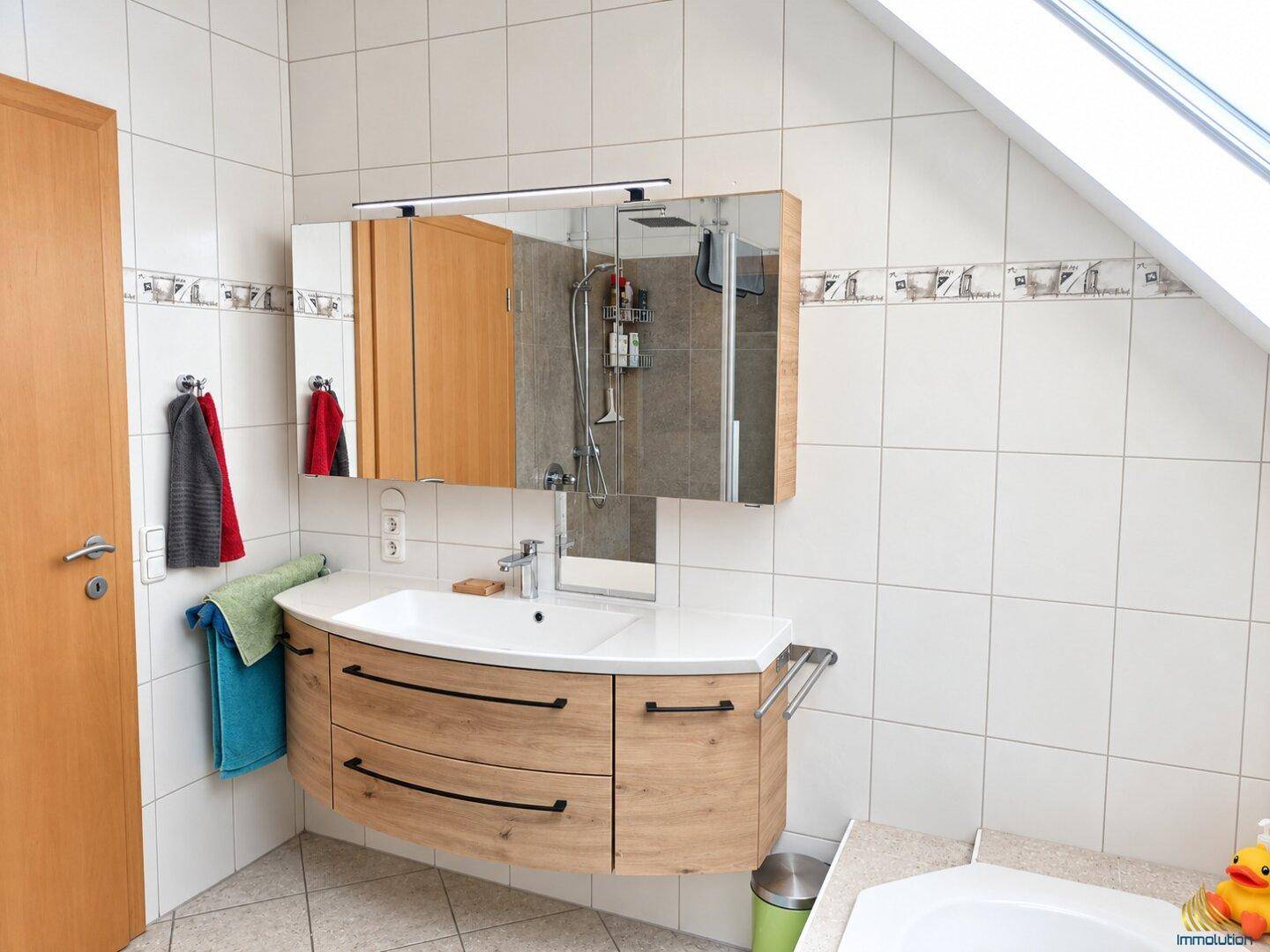 Badezimmer mit modernem Waschtisch, Einzelwaschbecken und Spiegelschrank.
