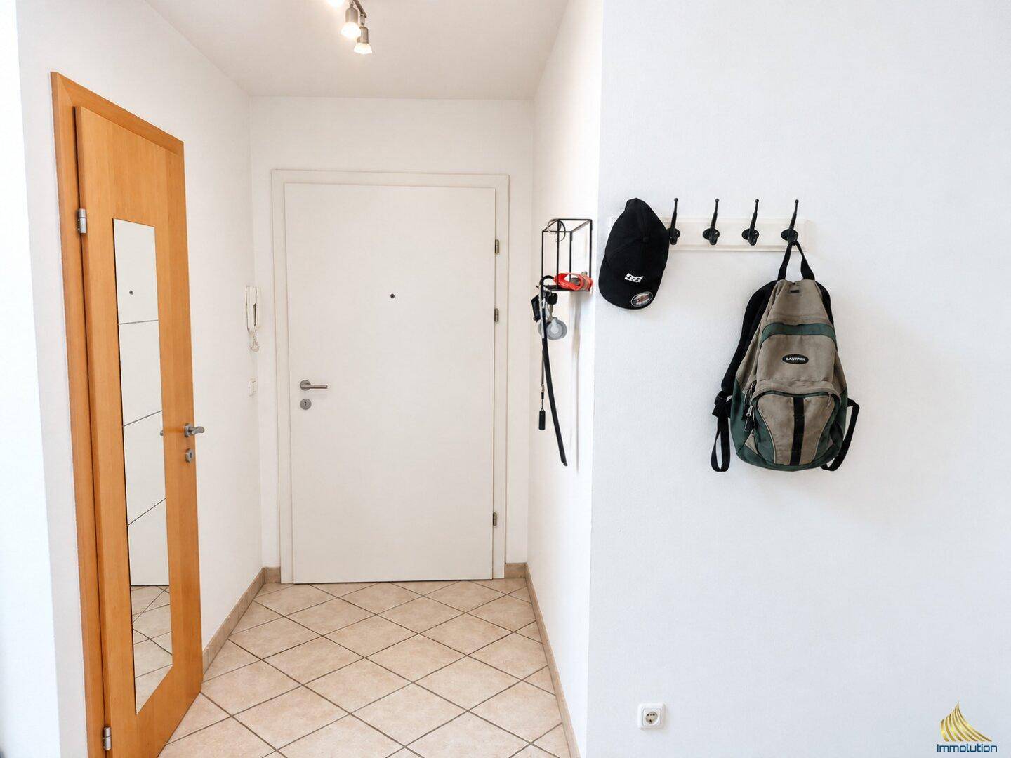 Heller Flur mit Eingangstür, Garderobe und Fliesenboden.