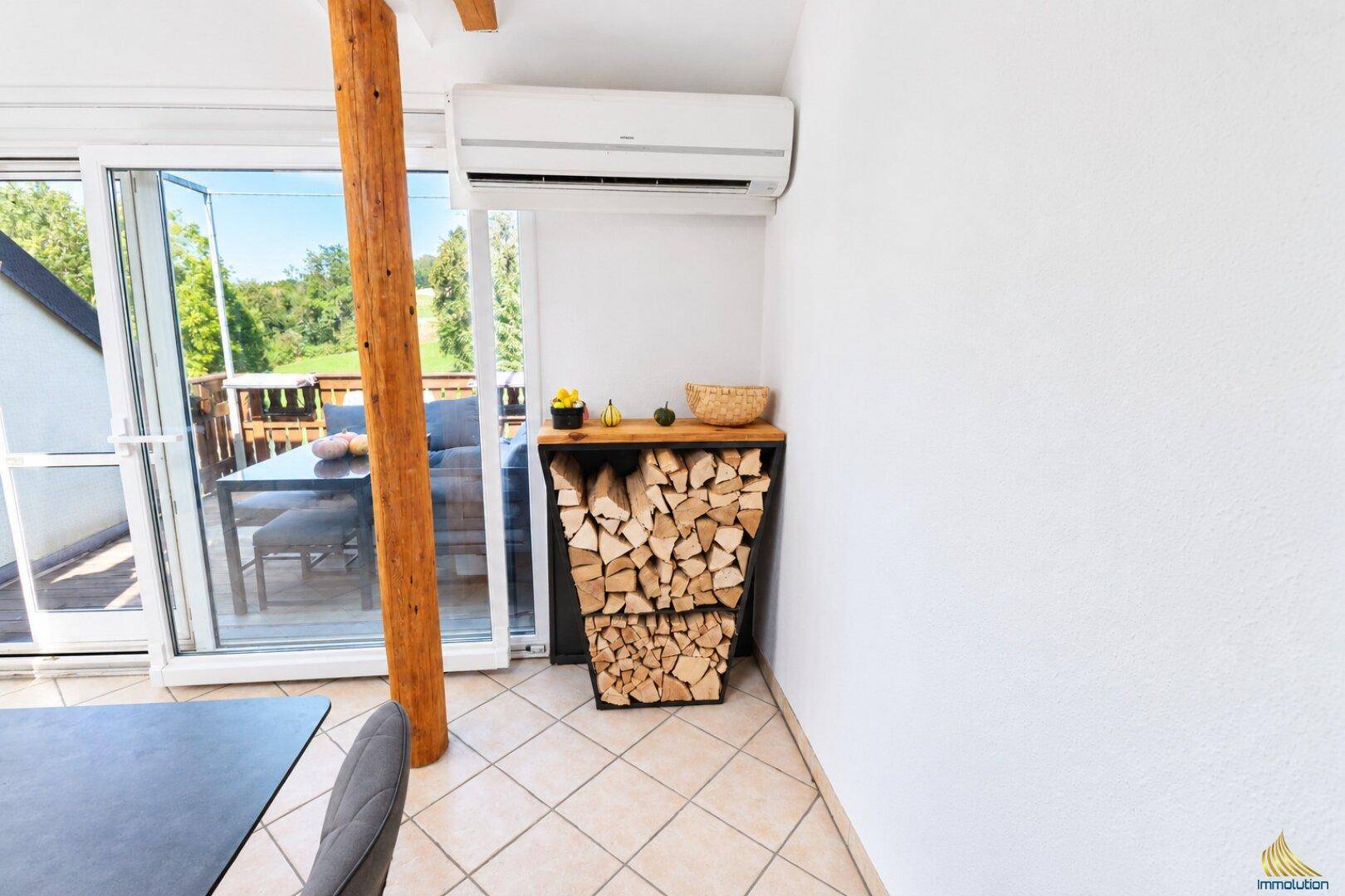 Innenbereich mit Holzstapel, Klimaanlage und Zugang zu einem Außenbereich.