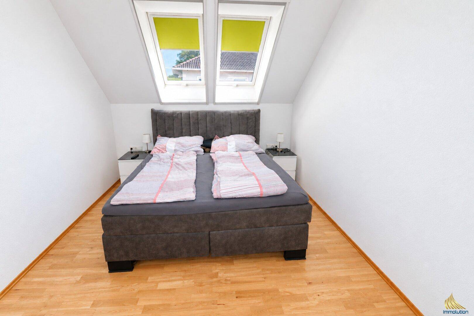 Schlafzimmer im Dachgeschoss mit Doppelbett, Holzboden und zwei Dachfenstern.
