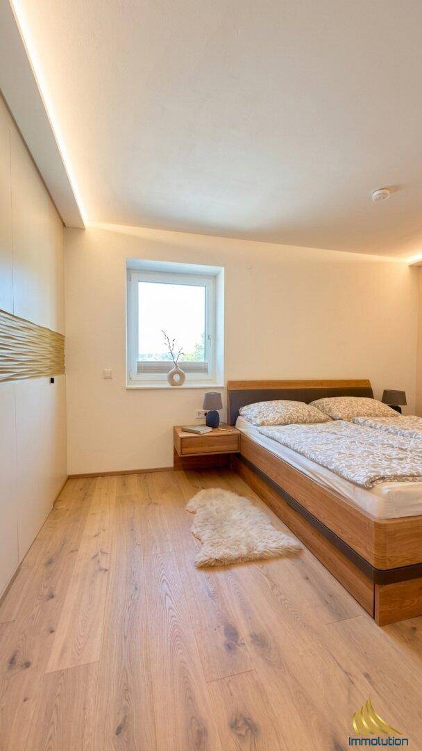 Modernes Schlafzimmer mit Holzbett, indirekter Beleuchtung und Parkettboden.