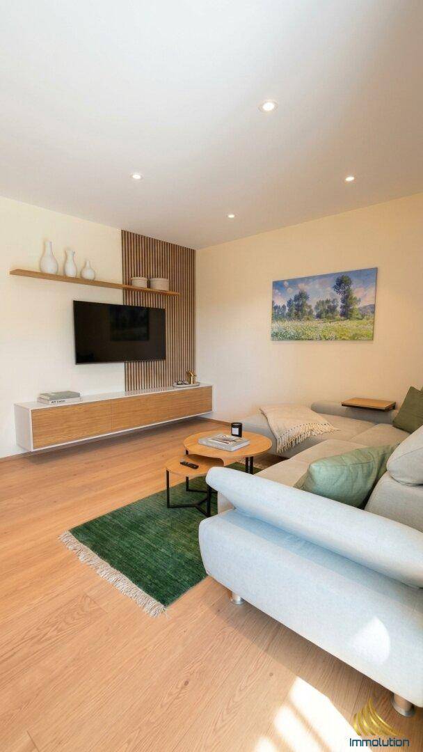 Gemütliches Wohnzimmer mit großem Sofa, modernem TV-Möbel und Holzboden.