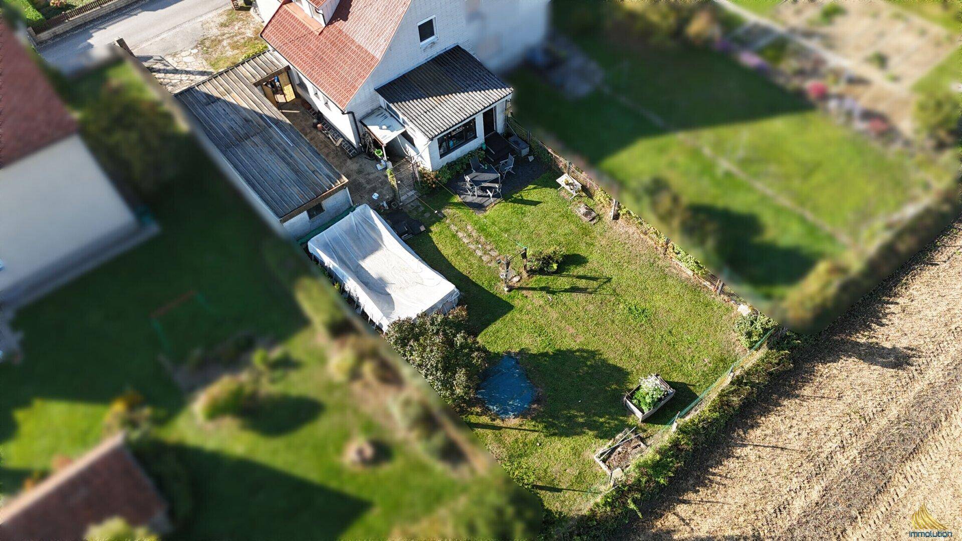 Großer Gartenbereich mit Rasenfläche, kleinem Teich und einem überdachten Pool.