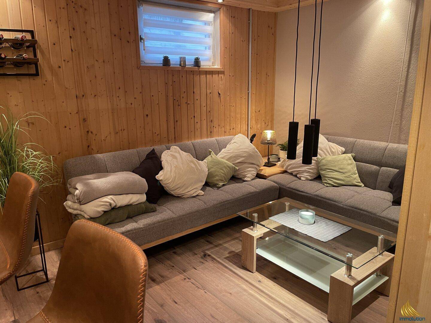 Rustikaler Wohnbereich mit Holzvertäfelung, Ecksofa und modernem Couchtisch.