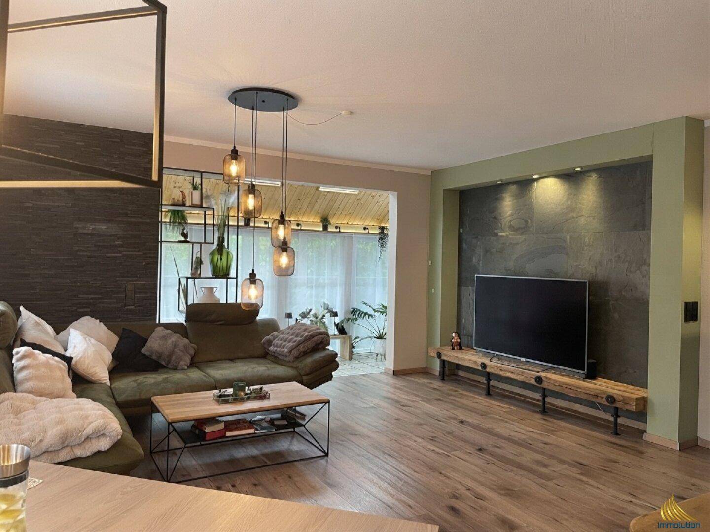 Geräumiges Wohnzimmer mit großem Sofa, Holzboden und modernem TV-Bereich.