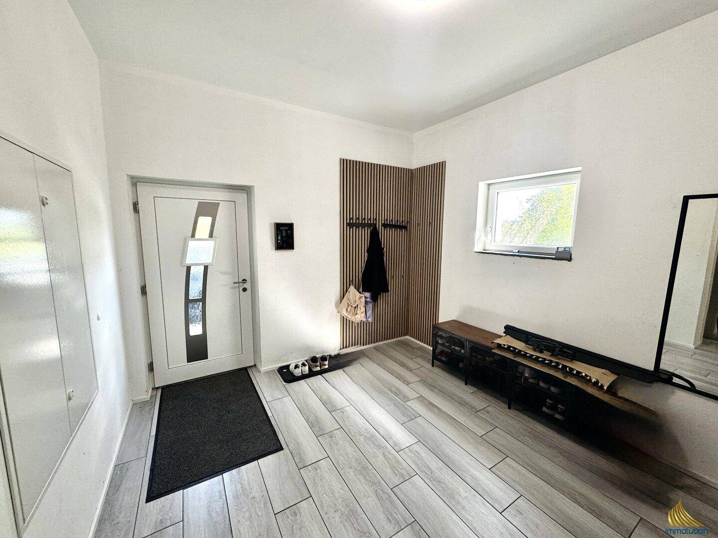 Eingangsbereich mit Fliesenboden, Garderobe und einem kleinen Fenster für Tageslicht.