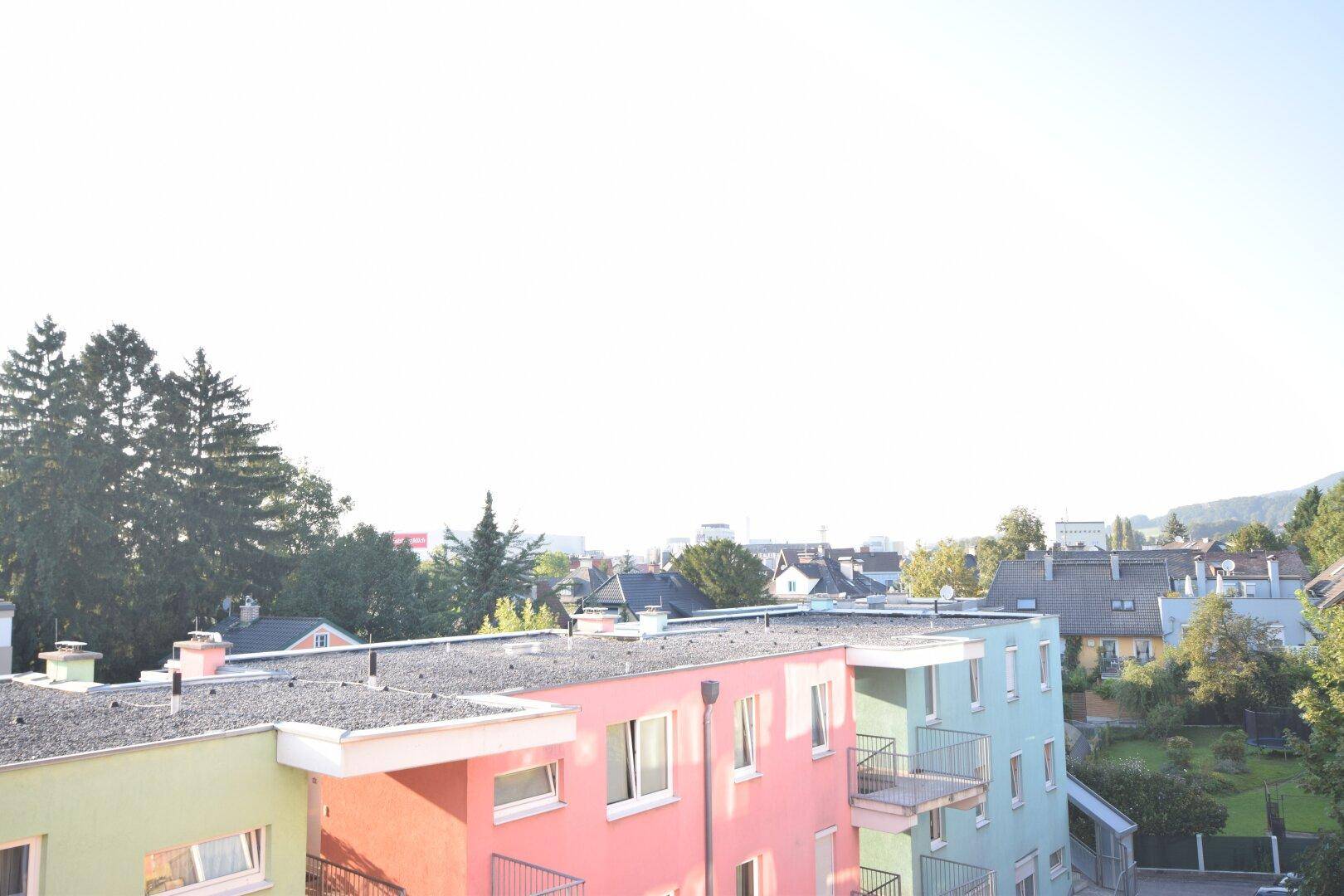 Blick über eine Wohnsiedlung mit farbenfrohen Gebäudefassaden und viel Grün in der Umgebung.