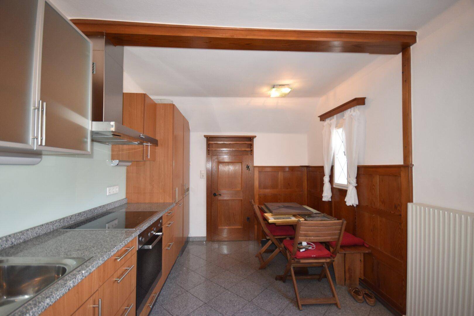 Gemütliche Wohnküche mit Holzvertäfelung, Granitarbeitsplatte und Essbereich.