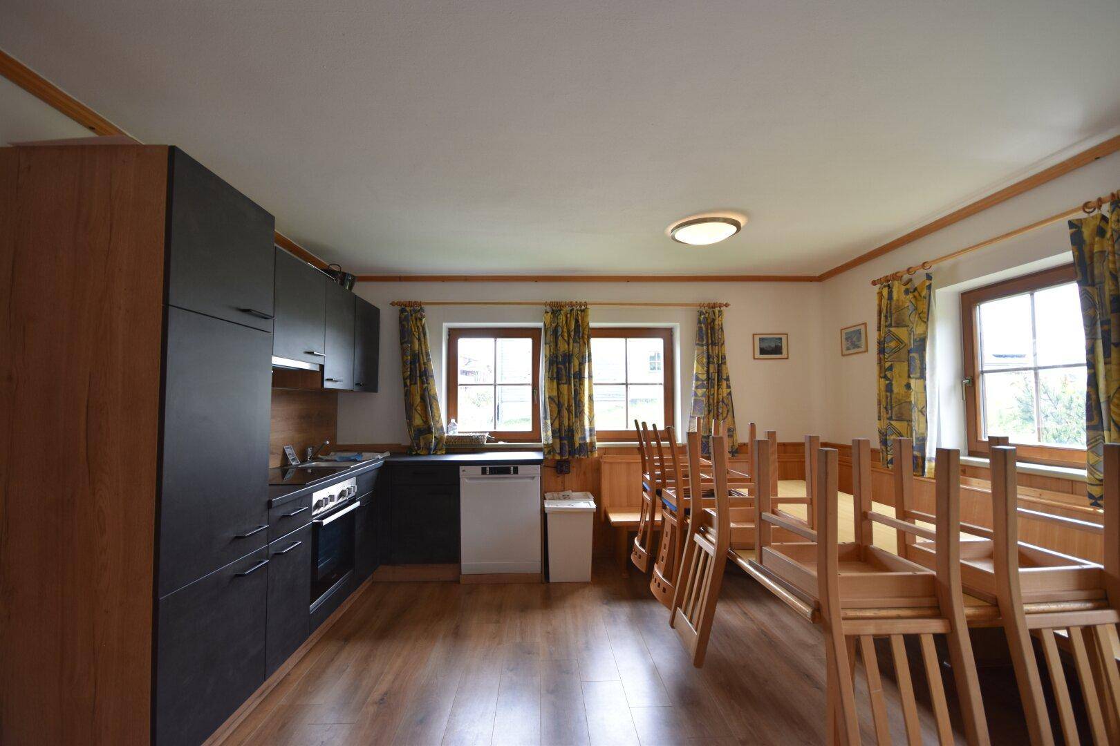 Gemütliche Küche mit dunklen Schränken, Holzboden und Esstisch im Landhausstil.