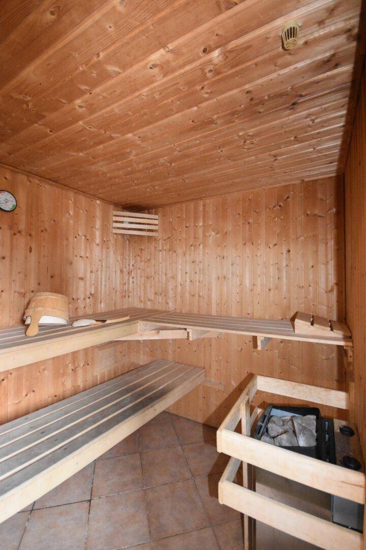 Traditionelle Holzsauna mit Bänken und Saunaofen für entspannende Momente.