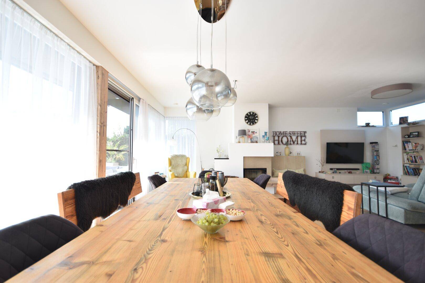 Geräumiger Essbereich mit großem Holztisch, Bänken und modernen Hängelampen.