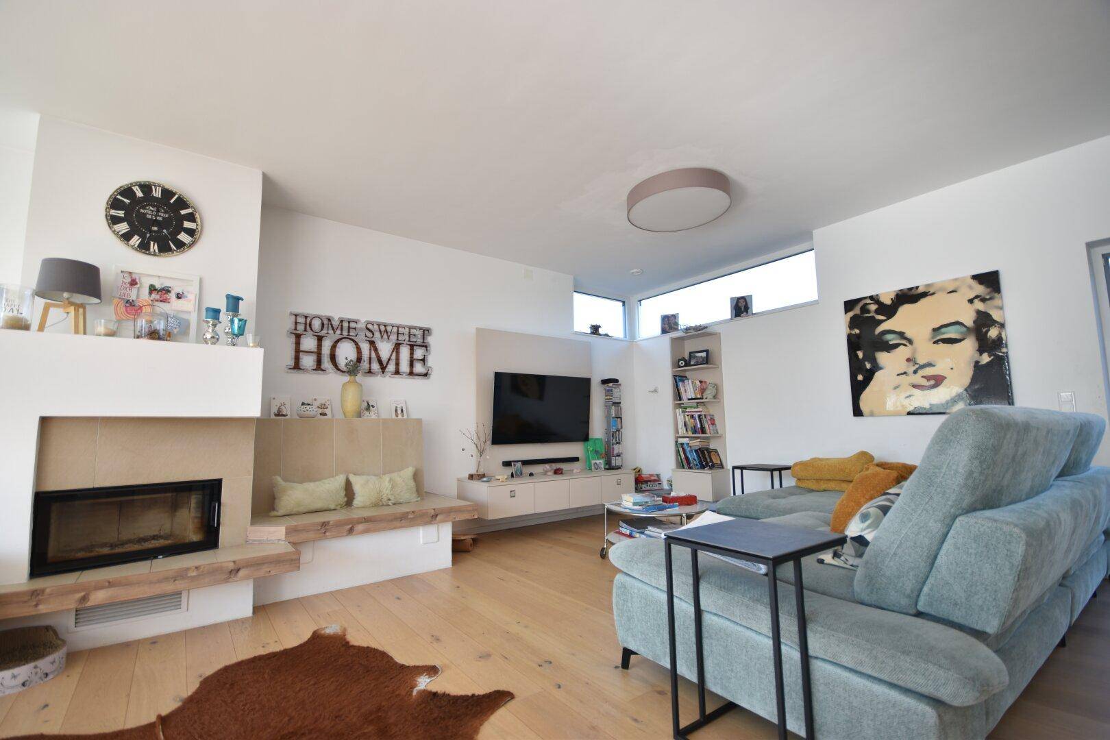 Helles Wohnzimmer mit Kamin, bequemer Couch und Holzboden.