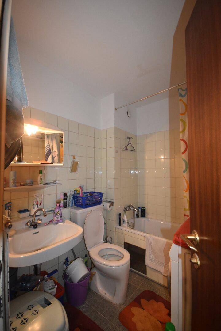Badezimmer mit Badewanne, Waschbecken und WC, ausgestattet mit hellen Wandfliesen.