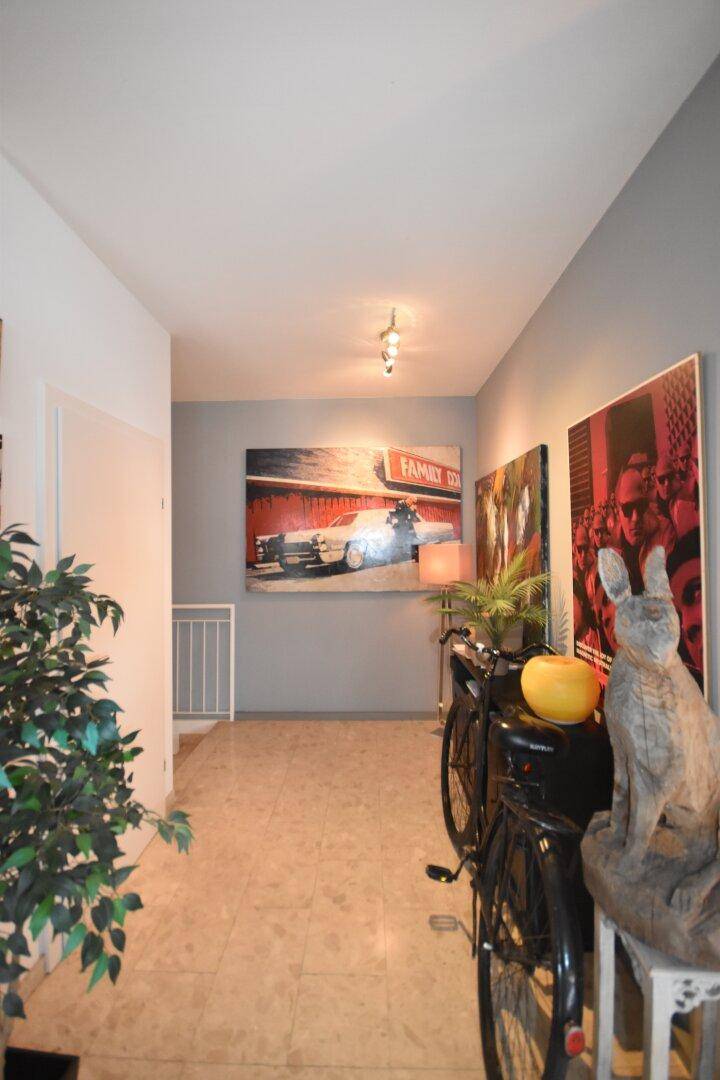 Heller Flur mit Kunstwerken an den Wänden und einem Fahrrad als Dekoration.