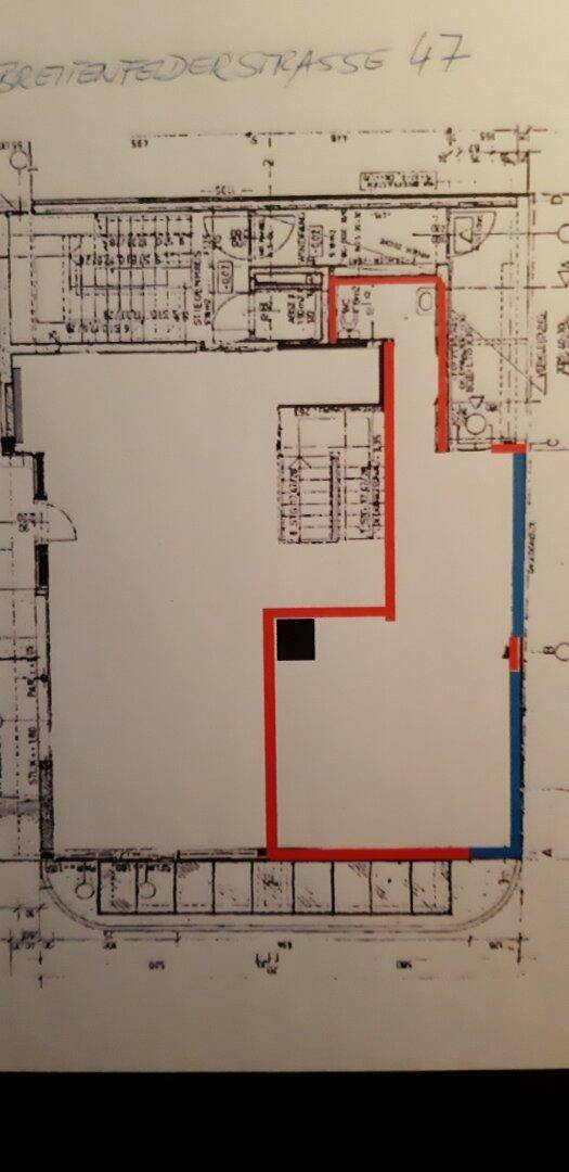 Architektonische Skizze eines Grundrisses mit markierten Bereichen und Treppenhaus.