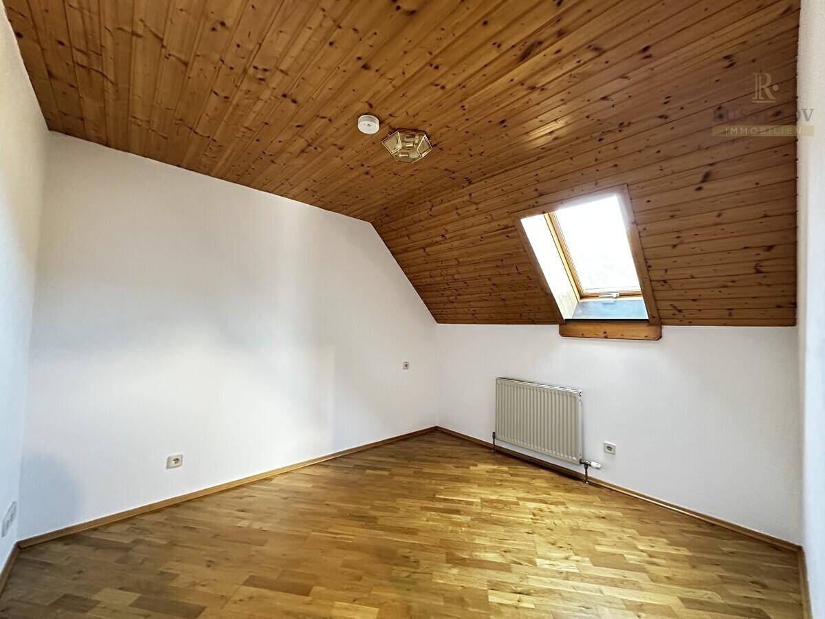 Helles Zimmer mit Holzboden, Dachschräge und Dachfenster für zusätzliches Tageslicht.