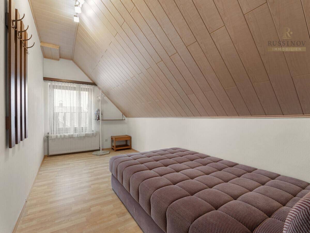 Vielseitiger Raum im Dachgeschoss mit Holzdachschräge und Laminatboden.