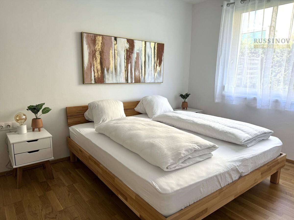 Helles Schlafzimmer mit Holzbett, Nachttischen und großem Fenster.