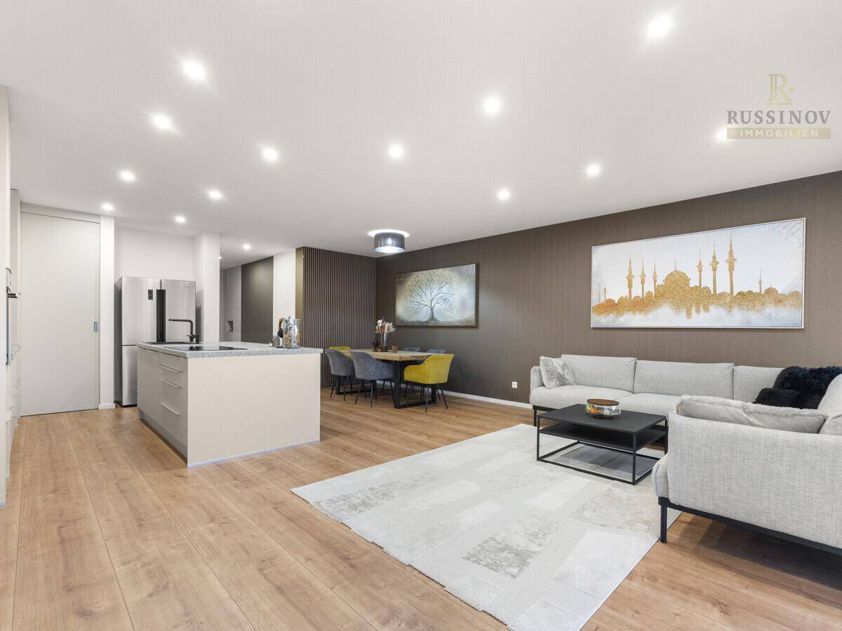 Geräumiger Wohn- und Essbereich mit moderner Einrichtung, Holzboden und Kunstwerken an den Wänden.