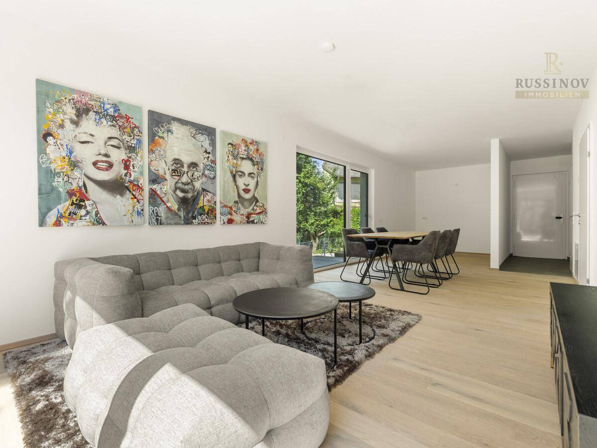 Gemütlicher Wohnbereich mit modernem Sofa, Kunstwerken und hellem Holzboden.