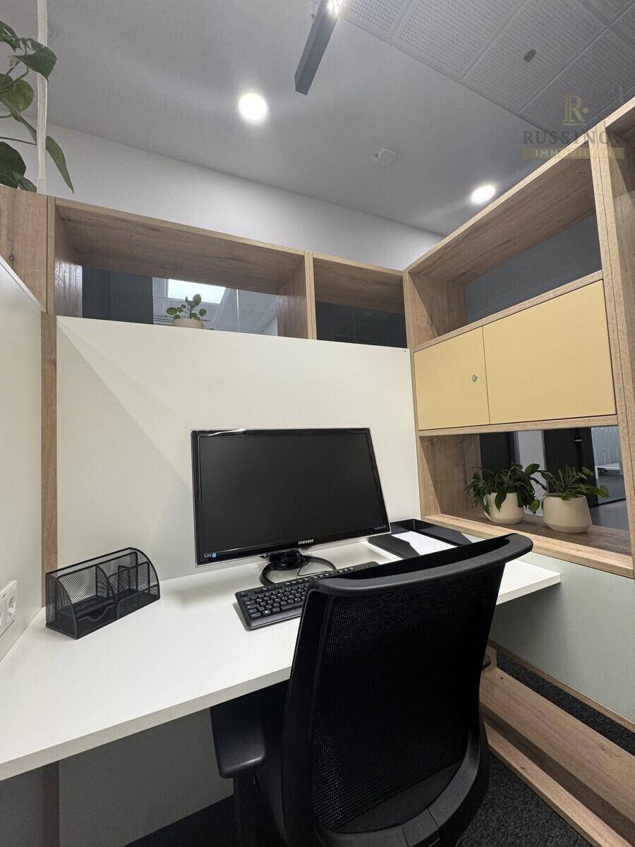 Individueller Arbeitsplatz in einem modernen Büro mit Monitor, Bürostuhl und integrierten Regalen.