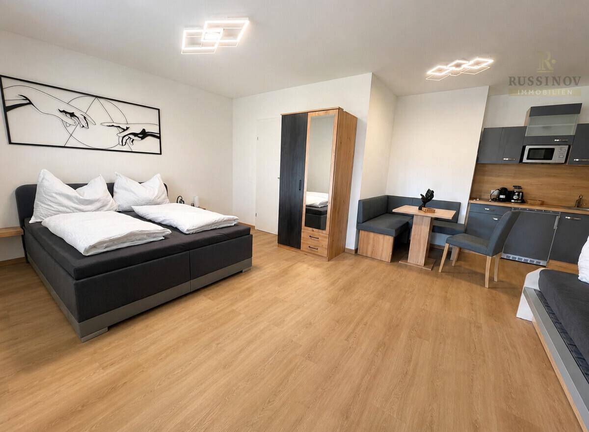 Modernes Studio-Apartment mit Doppelbett, Essbereich und integrierter Küchenzeile.