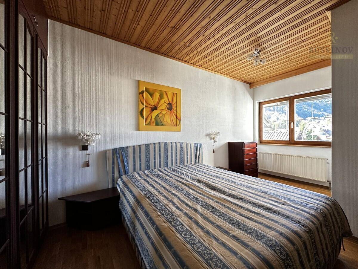Gemütliches Schlafzimmer mit Holzdecke, Holzboden und Fenster mit Bergblick.