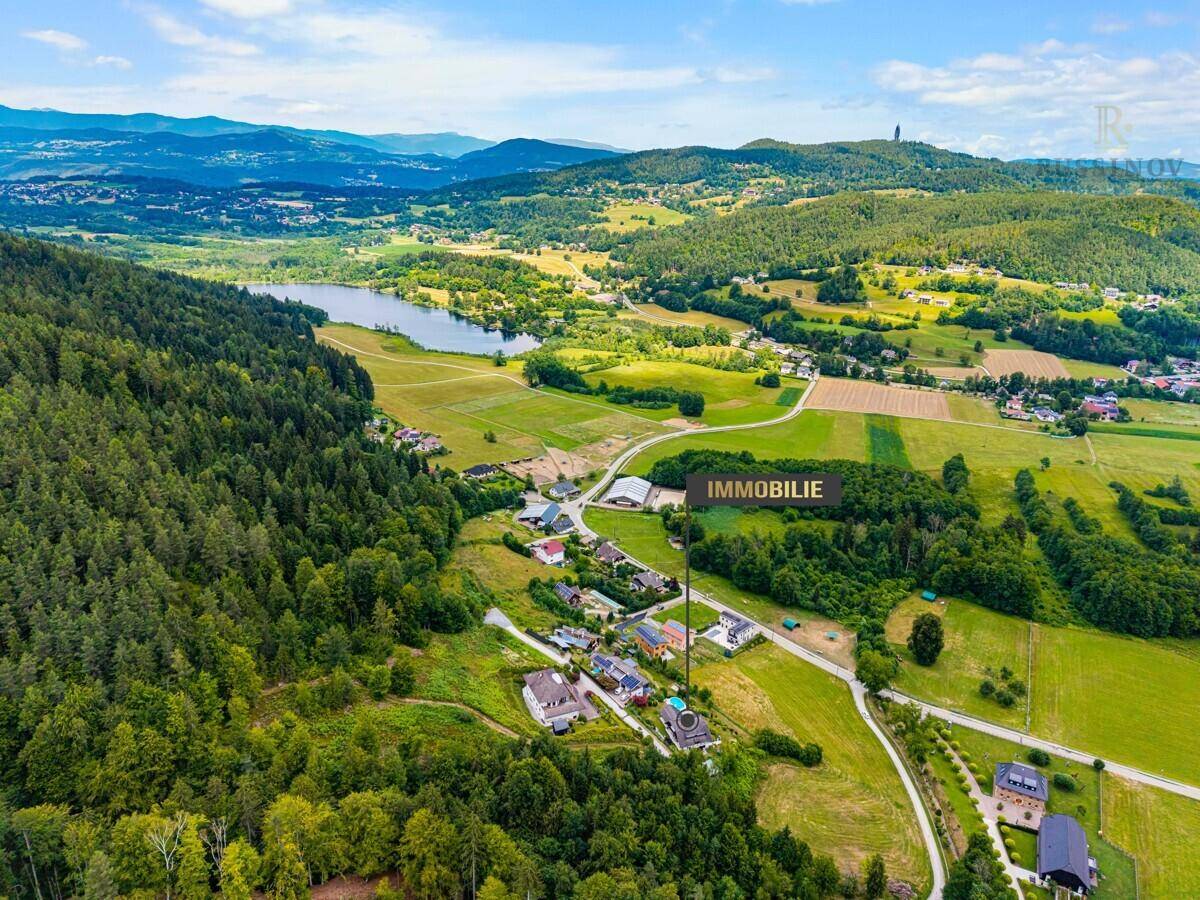 Luftaufnahme des Anwesens in ländlicher Umgebung mit See und Wäldern im Hintergrund.