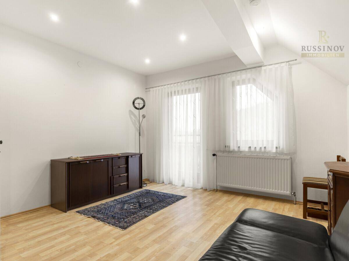 Heller Raum im Dachgeschoss mit Dachschräge und Laminatboden.