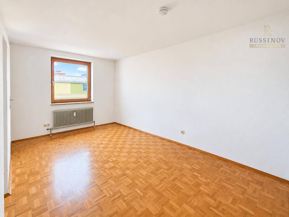 Geräumiges Wohnzimmer mit klassischem Parkettboden und viel Tageslicht.